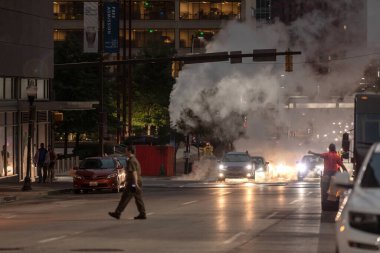 Baltimore, Maryland - October 03, 2019: Traffic in Baltimore, Maryland. USA. Hot Water Steam in Background. Downtown Street