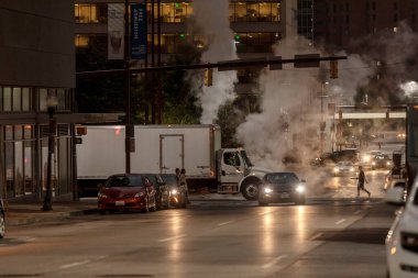 Baltimore, Maryland - October 03, 2019: Traffic in Baltimore, Maryland. USA. Hot Water Steam in Background. Downtown Street