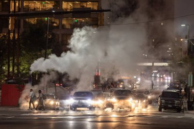 Baltimore, Maryland - October 03, 2019: Traffic in Baltimore, Maryland. USA. Hot Water Steam in Background. Downtown Street