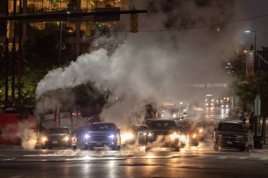 Baltimore, Maryland - October 03, 2019: Traffic in Baltimore, Maryland. USA. Hot Water Steam in Background. Downtown Street