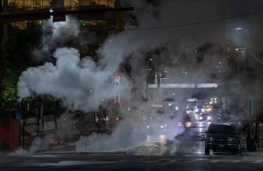 Baltimore, Maryland - October 03, 2019: Traffic in Baltimore, Maryland. USA. Hot Water Steam in Background. Downtown Street