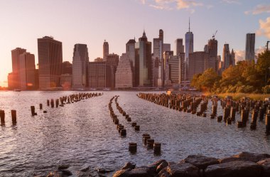 Beautiful Sunset and Lower Manhattan skyline with East River and New York City. Twilight with Reflections and Abandoned Pier at Sunset from Brooklyn Bridge Park