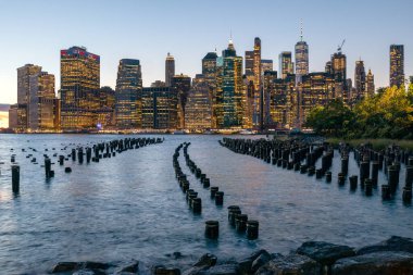 Beautiful Sunset and Lower Manhattan skyline with East River and New York City. Twilight with Reflections and Abandoned Pier at Sunset from Brooklyn Bridge Park