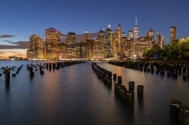 Beautiful Night Light and Lower Manhattan skyline with East River and New York City. Twilight with Reflections and Abandoned Pier at Sunset from Brooklyn Bridge Park