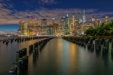 Beautiful Night Light and Lower Manhattan skyline with East River and New York City. Twilight with Reflections and Abandoned Pier at Sunset from Brooklyn Bridge Park