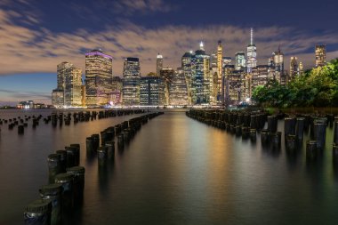 Beautiful Night Light and Lower Manhattan skyline with East River and New York City. Twilight with Reflections and Abandoned Pier at Sunset from Brooklyn Bridge Park