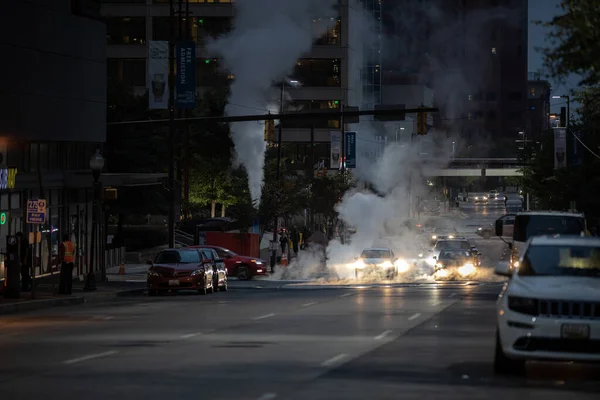 Baltimore, Maryland - October 03, 2019: Traffic in Baltimore, Maryland. USA. Hot Water Steam in Background. Downtown Street