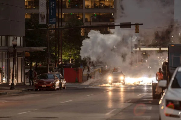 Baltimore, Maryland - October 03, 2019: Traffic in Baltimore, Maryland. USA. Hot Water Steam in Background. Downtown Street