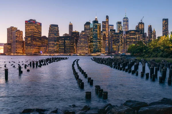 Beautiful Sunset and Lower Manhattan skyline with East River and New York City. Twilight with Reflections and Abandoned Pier at Sunset from Brooklyn Bridge Park