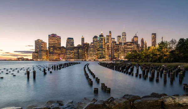 Beautiful Sunset and Lower Manhattan skyline with East River and New York City. Twilight with Reflections and Abandoned Pier at Sunset from Brooklyn Bridge Park