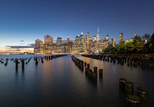 Beautiful Sunset and Lower Manhattan skyline with East River and New York City. Twilight with Reflections and Abandoned Pier at Sunset from Brooklyn Bridge Park