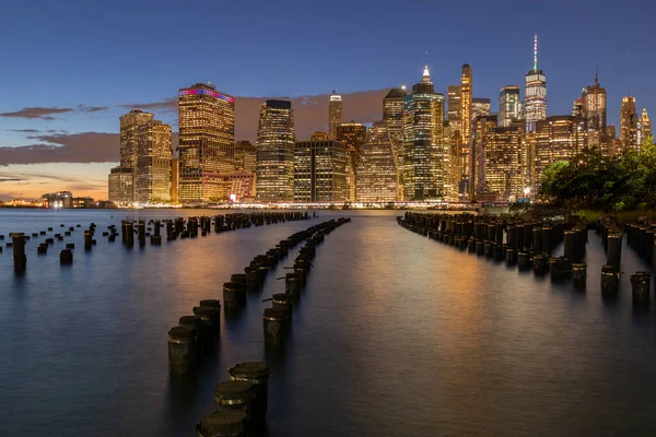 Beautiful Night Light and Lower Manhattan skyline with East River and New York City. Twilight with Reflections and Abandoned Pier at Sunset from Brooklyn Bridge Park