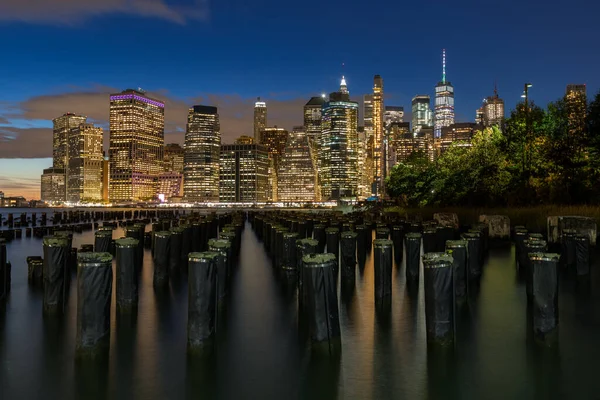 Beautiful Night Light and Lower Manhattan skyline with East River and New York City. Twilight with Reflections and Abandoned Pier at Sunset from Brooklyn Bridge Park