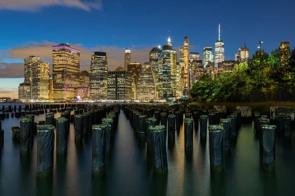 Beautiful Night Light and Lower Manhattan skyline with East River and New York City. Twilight with Reflections and Abandoned Pier at Sunset from Brooklyn Bridge Park