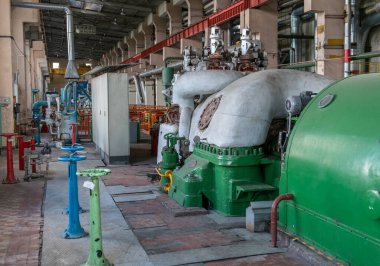 Industrial machines. Internal structure of large thermal power plant. The interior of an industrial boiler room with many pipes, valves and sensors. Steam turbine and electricity generator