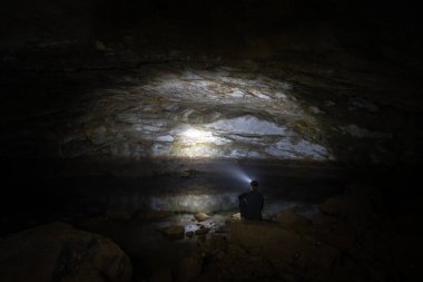 Girl is Sitting in Tounjcica cave in Croatia. Sightseeing Object in Tounj. It is a village and a municipality in Karlovac County, Croatia. Clear Water and Reflection on it.
