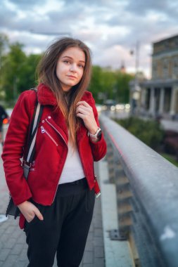 Litvanya 'nın başkenti Vilnius' taki Mindaugas Köprüsü 'nde duran güzel Litvanyalı kız. Kırmızı Ceket Giyiyor. Geriye bakıyorum. Günbatımı Işığı