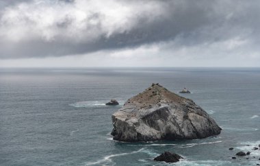 Pacific Ocean and Rocks in the Water. Next to California State Road 1. Cloudy Stormy Sky in Background. Wild Nature