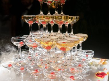 Champagne glasses standing in a tower at the wedding party. Champagne glass pyramid. Pyramid of glasses of wine, champagne, tower of champagne. Wedding party at night