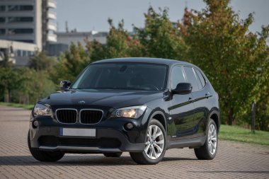 BMW X1 2012 Year R18 Wheels is a compact sport utility vehicle. Black Color. Beautiful Sunny Background.