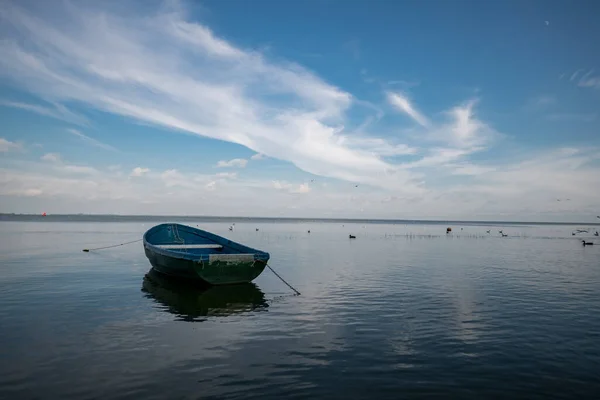 Single Boat in Calm Sea Water. Cloudy Blue Sky