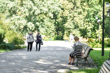 VILNIUS, LITHUANIA - 31 AĞUSTOS 2017: Litvanya, Vilnius 'taki Kamu Parkı. Bankta oturan yaşlı kadın.