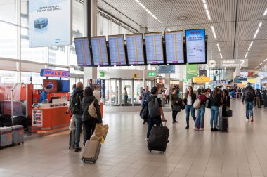 AMSTERDAM, NETHERLAND - 18 Ekim 2017: Uluslararası Amsterdam Havalimanı Schiphol İçişleri Yolcularıyla. Ekranlar ve Arkaplanda İnsanlar.
