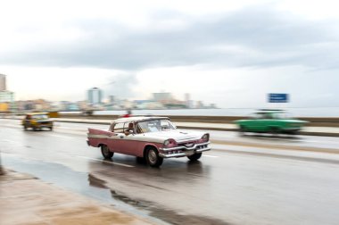 HAVANA, CUBA - 21 Ekim 2017: Havana, Küba 'daki eski araba. Pannnig. Retro Araç genellikle yerel halk ve turistler için bir taksi olarak kullanılır. Arka planda Karayip Denizi. Pembe Renk