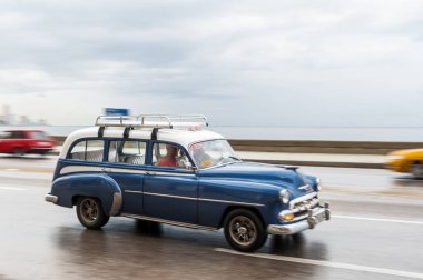 HAVANA, CUBA - 21 Ekim 2017: Havana, Küba 'daki eski araba. Retro Araç genellikle yerel halk ve turistler için bir taksi olarak kullanılır. Arka planda Karayip Denizi. Panning Mavi Renkli Araba