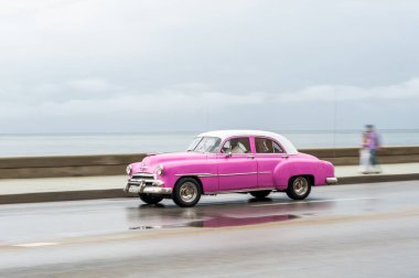 HAVANA, CUBA - 21 Ekim 2017: Havana, Küba 'daki eski araba. Retro Araç genellikle yerel halk ve turistler için bir taksi olarak kullanılır. Arka planda Karayip Denizi. Panning Pembe Renkli Araba