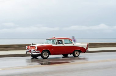 HAVANA, CUBA - 21 Ekim 2017: Havana, Küba 'daki eski araba. Retro Araç genellikle yerel halk ve turistler için bir taksi olarak kullanılır. Arka planda Karayip Denizi. Panning Kırmızı Renkli Araba