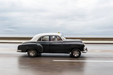 HAVANA, CUBA - 21 Ekim 2017: Havana, Küba 'daki eski araba. Retro Araç genellikle yerel halk ve turistler için bir taksi olarak kullanılır. Arka planda Karayip Denizi. Panning Siyah Renkli Araba