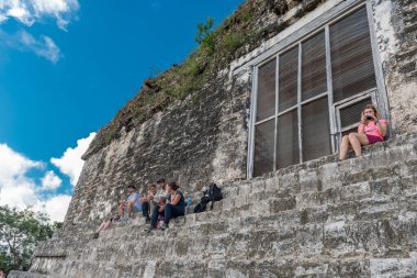 Guatemala - 7 Kasım 2017 'de insanlar Tikal Park' taki Piramit ve Tapınak 'ta oturuyorlar. Guatemala 'da Maya tapınakları ve seremoni kalıntıları olan gezici bir nesne. Tikal, Kuzey Guatemala 'daki yağmur ormanlarında bulunan antik bir Maya Kalesidir..