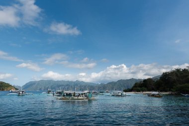 CORON, FİLİPPİNLER - 30 HAZİRAN 2018: tekneler turistleri bekliyor. CYC adası ve arka plandaki plaj. Koron, Filipinler.