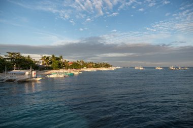 MALAPASCUA, PHILIPPINES - 7 Şubat 2018: Malapascua, Filipinler 'deki boş plaj. Açık mavi gökyüzü ve okyanus suyu, kumlu sahil ve tekneler.