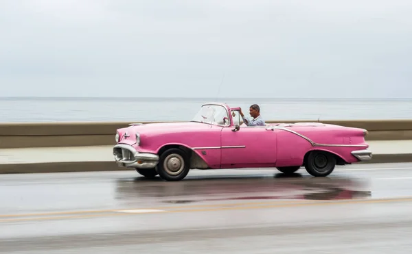 stock image HAVANA, CUBA - OCTOBER 21, 2017: Old Car in Havana, Cuba. Pannnig. Retro Vehicle Usually Using As A Taxi For Local People and Tourist. Caribbean Sea in Background. Pink Color