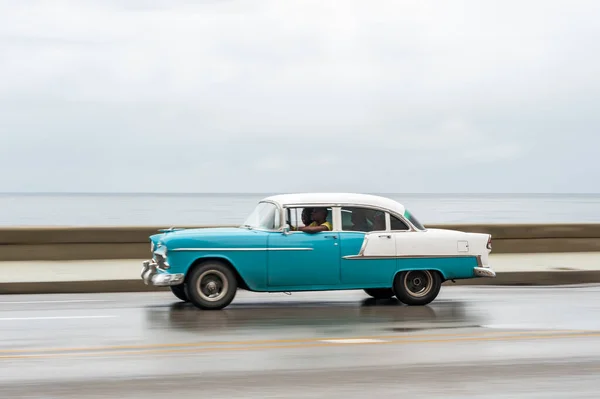 stock image HAVANA, CUBA - OCTOBER 21, 2017: Old Car in Havana, Cuba. Retro Vehicle Usually Using As A Taxi For Local People and Tourist. Caribbean Sea in Background. Panning Blue Color Car