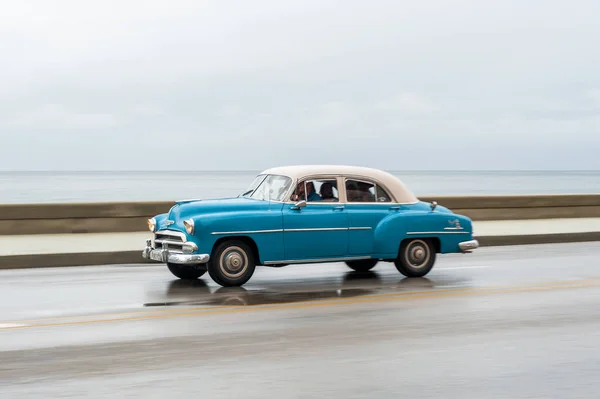 stock image HAVANA, CUBA - OCTOBER 21, 2017: Old Car in Havana, Cuba. Retro Vehicle Usually Using As A Taxi For Local People and Tourist. Caribbean Sea in Background. Panning Blue Color Car