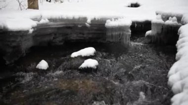 Bir nehrin kış manzarası, su yavaşça nehirden aşağı akıyor. Nehirde eriyen buzlar. Litvanya
