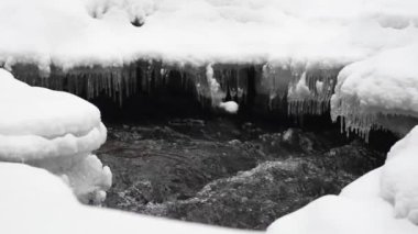 Bir nehrin kış manzarası, su yavaşça nehirden aşağı akıyor. Nehirde eriyen buzlar. Litvanya. Yavaş Hareket