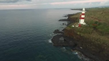 Mauritius adası ve arka planda kayalık kıyı şeridi. Arka planda deniz feneri var. Phare d'Albion
