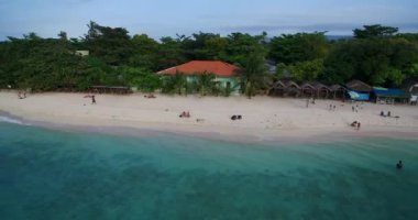 Filipinler, Cebu, Moalboal 'da tekneler, beyaz plajlar ve deniz kıyıları. Seashore ve Arkaplanda İnsanlar 'la güzel bir manzara. 4k İHA