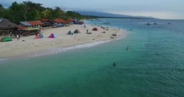 Filipinler, Cebu, Moalboal 'da tekneler, beyaz plajlar ve deniz kıyıları. Seashore ve Arkaplanda İnsanlar 'la güzel bir manzara. 4k İHA