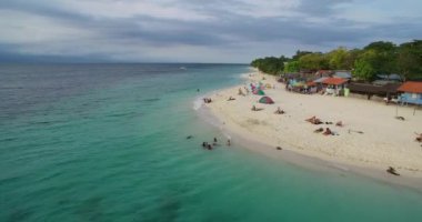 Filipinler, Cebu, Moalboal 'da tekneler, beyaz plajlar ve deniz kıyıları. Seashore ve Arkaplanda İnsanlar 'la güzel bir manzara. 4k İHA