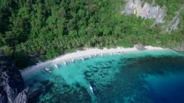 Palawan 'da Yedi Komando ve Papaya Sahili, Manzara Mekanı. El Nido, Filipinler 'de A turu. Berrak turkuaz suyu olan sakin, beyaz kumlu plaj, arka planda palmiye ağaçları, kaya oluşumları. İHA