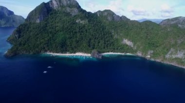 Palawan 'da Yedi Komando ve Papaya Sahili, Manzara Mekanı. El Nido, Filipinler 'de A turu. Berrak turkuaz suyu olan sakin, beyaz kumlu plaj, arka planda palmiye ağaçları, kaya oluşumları. İHA