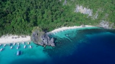 Palawan 'da Yedi Komando ve Papaya Sahili, Manzara Mekanı. El Nido, Filipinler 'de A turu. Berrak turkuaz suyu olan sakin, beyaz kumlu plaj, arka planda palmiye ağaçları, kaya oluşumları. İHA
