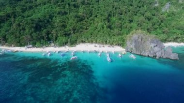 Palawan 'da Yedi Komando ve Papaya Sahili, Manzara Mekanı. El Nido, Filipinler 'de A turu. Berrak turkuaz suyu olan sakin, beyaz kumlu plaj, arka planda palmiye ağaçları, kaya oluşumları. İHA