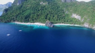 Palawan 'da Yedi Komando ve Papaya Sahili, Manzara Mekanı. El Nido, Filipinler 'de A turu. Berrak turkuaz suyu olan sakin, beyaz kumlu plaj, arka planda palmiye ağaçları, kaya oluşumları. İHA