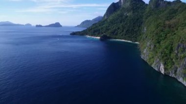 Palawan 'da Yedi Komando ve Papaya Sahili, Manzara Mekanı. El Nido, Filipinler 'de A turu. Berrak turkuaz suyu olan sakin, beyaz kumlu plaj, arka planda palmiye ağaçları, kaya oluşumları. İHA